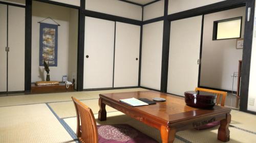 a room with a wooden table and chairs and cabinets at 白水温泉竹の倉山荘 in Minami Aso