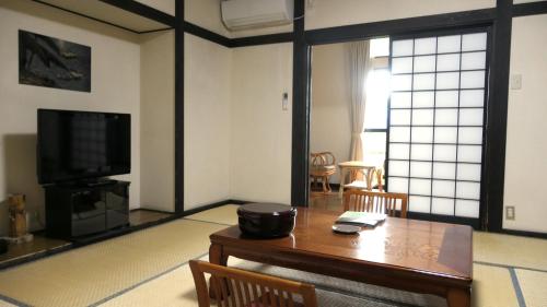 a living room with a table and a tv at 白水温泉竹の倉山荘 in Minami Aso