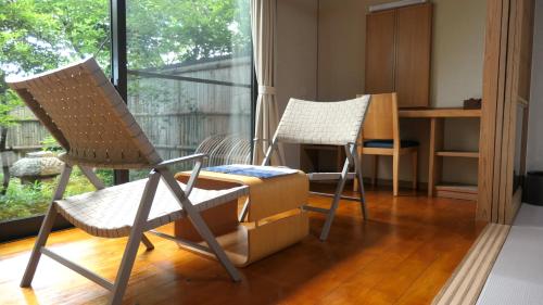a living room with two chairs and a table at 白水温泉竹の倉山荘 in Minami Aso