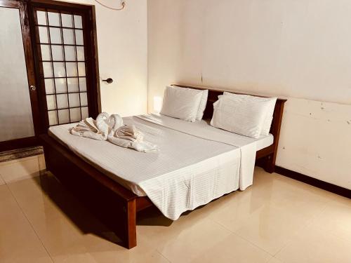 a bedroom with a bed with white sheets and towels at Eco Boutique Villa in Gurudeniya