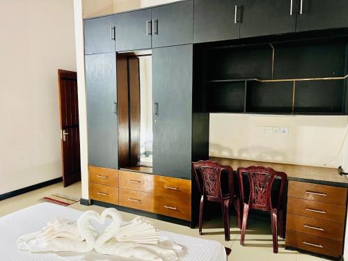 a room with two chairs and a kitchen with cabinets at Eco Boutique Villa in Gurudeniya