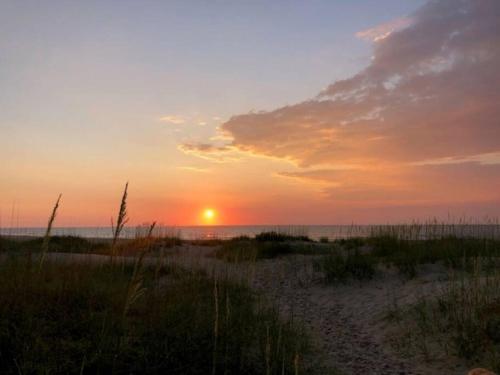 a sunset on the beach with the sun setting at Captain's Quarters in Avon