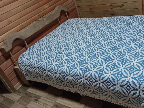 a bed with a blue and white blanket on it at Sítio lampião do norte in Blinha