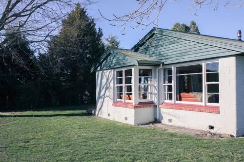 a small house with a large window in a yard at Green Keeper's Bach- Perfect Family Choice in Methven
