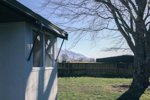 a window on the side of a house with a tree at Green Keeper's Bach- Perfect Family Choice in Methven