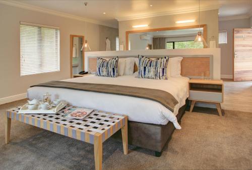 a large bedroom with a large bed and a table at Knysna Hollow Country Estate in Knysna