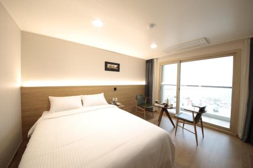 a bedroom with a large bed and a large window at Harbor Hotel in Jeju