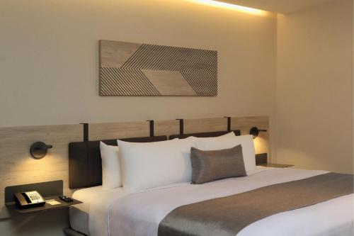 a bedroom with a bed and a picture on the wall at City Express Plus by Marriott Monterrey Centro in Monterrey