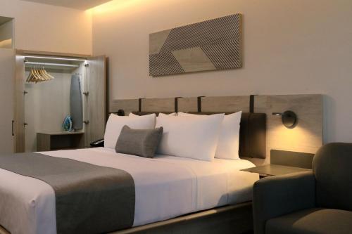 a hotel room with a large bed and a chair at City Express Plus by Marriott Monterrey Centro in Monterrey