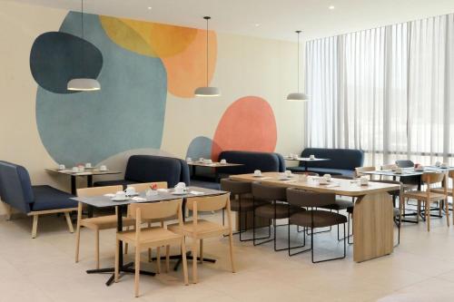 a dining room with tables and chairs and a mural at City Express Plus by Marriott Monterrey Centro in Monterrey