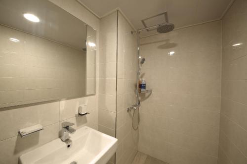 a white bathroom with a sink and a shower at Harbor Hotel in Jeju