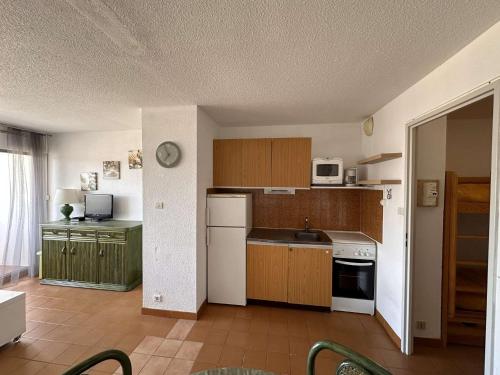 - une cuisine avec des placards en bois et des appareils blancs dans l'établissement Studio-cabine 4 pers, plage à 200m, parking privatif - FR-1-731-104, au Grau-du-Roi
