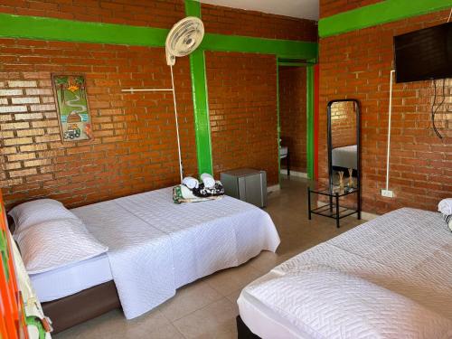 a bedroom with two beds and a brick wall at Finca La Gaviota in Montenegro
