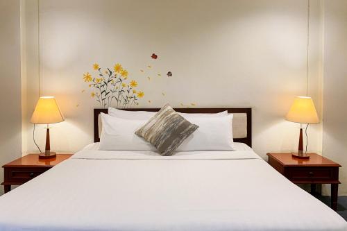 a bedroom with a large white bed with two lamps at rimtara residence patan in Chiang Mai