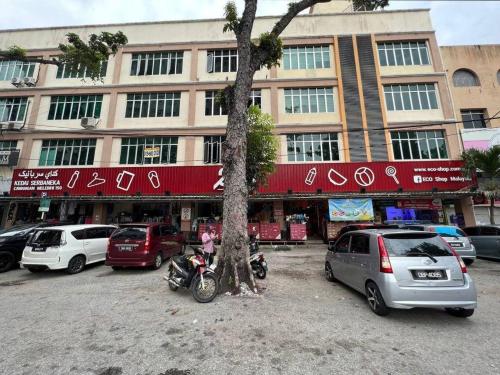 a tree and cars parked in front of a building at Homestay Ladang Deluxe Family Suite in Kuala Terengganu