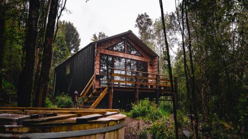 a log cabin in the woods with a deck at Puente Palos San Pedro in Castro