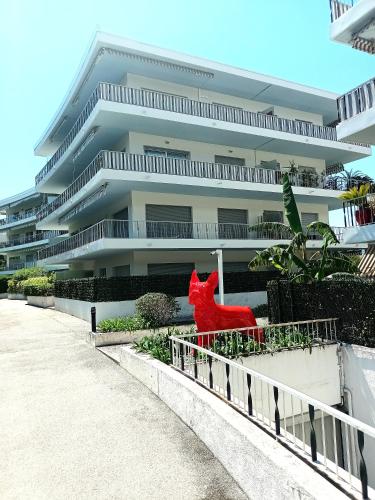une statue de chat rouge devant un bâtiment dans l'établissement Les Oliviers Big Terrace&Pool Comfy, à Roquebrune-Cap-Martin