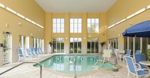 a swimming pool with blue chairs and a table and a tablektop at Hampton Inn Macomb in Macomb