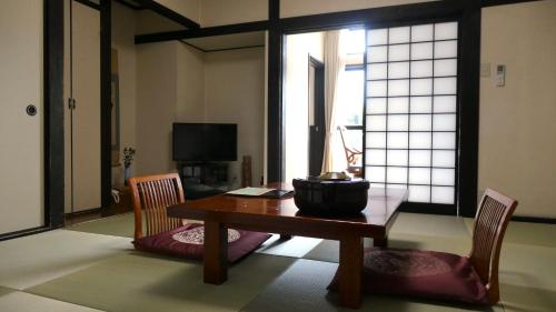 a living room with a table and two chairs at 白水温泉竹の倉山荘 in Minami Aso