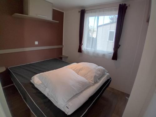 un lit dans une chambre avec une fenêtre dans l'établissement Mymobilhome 2 chambres Saint-Jean-de-Monts, à Saint-Jean-de-Monts