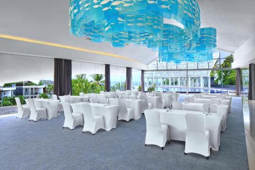 a room with white chairs and a large chandelier at Le Meridien Bali Jimbaran in Jimbaran