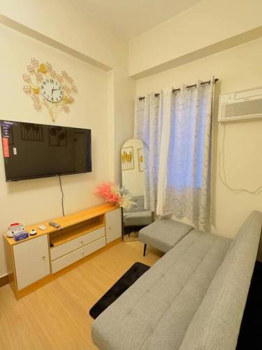 a living room with a couch and a flat screen tv at Zenrise Staycation Condo in SMDC Hope Residences Trece Martires in San Agustin
