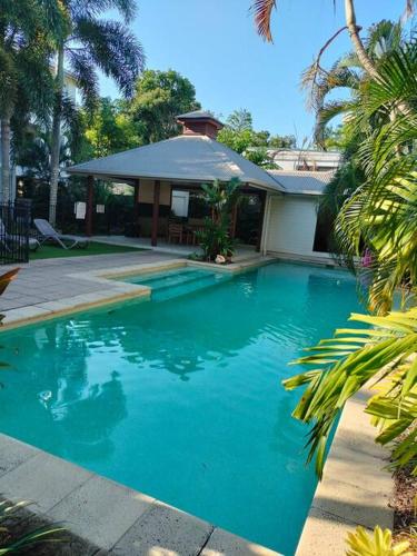 a blue swimming pool in front of a house at Studio close to Airport, City & Esplanade in Cairns North