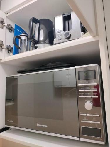 a microwave oven sitting on a shelf in a kitchen at Studio close to Airport, City & Esplanade in Cairns North