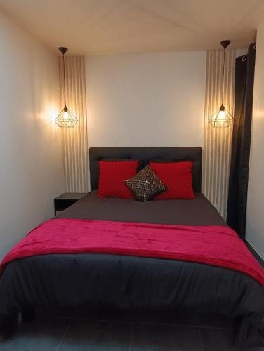 une chambre avec un grand lit avec deux oreillers rouges dans l'établissement Évasion romantique avec jacuzzi intérieur, à Rosières-près-Troyes