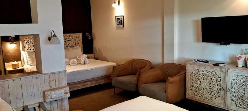 a room with a bed and a chair and a tv at Ru Boutique in Kandy