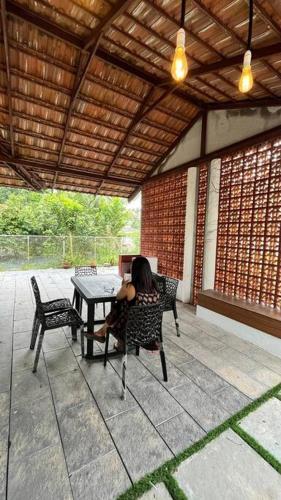 a woman sitting at a table on a patio at Traditional house near Kochi in Cochin