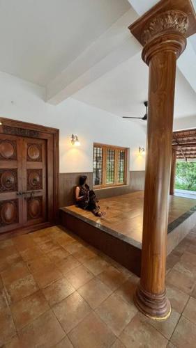 a person sitting on a couch in a room with a pole at Traditional house near Kochi in Cochin