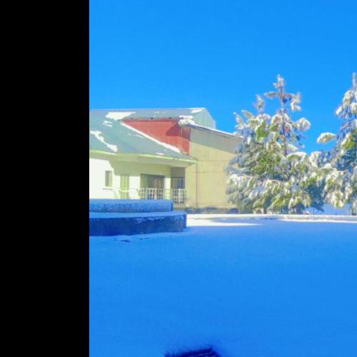a house with a snow covered tree in front of a building at Lovely 1 bedroom condo with majestic views in Bhurban