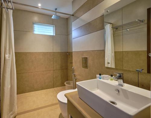 a bathroom with a sink and a toilet and a mirror at Tea Garden Riverside in Munnar