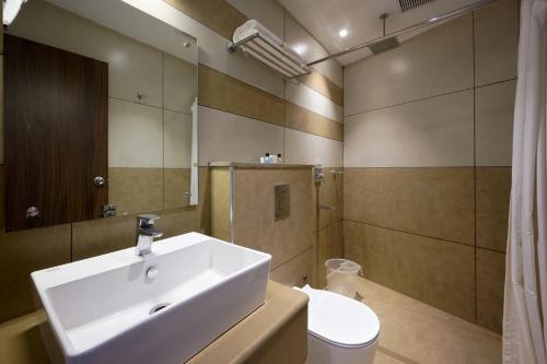 a bathroom with a sink and a toilet and a mirror at Tea Garden Riverside in Munnar