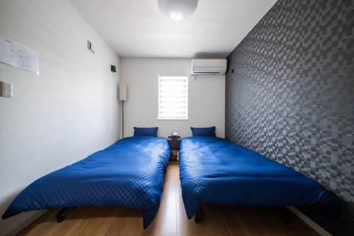 two beds in a room with blue pillows at Apollo in Hakodate