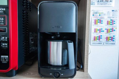 a black coffee maker sitting next to a microwave at Apollo in Hakodate