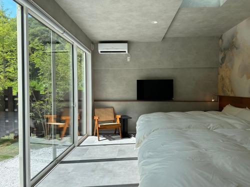 a bedroom with a bed and a balcony with a tv at LOCA THE JUNPU Moroyose in Moroyose