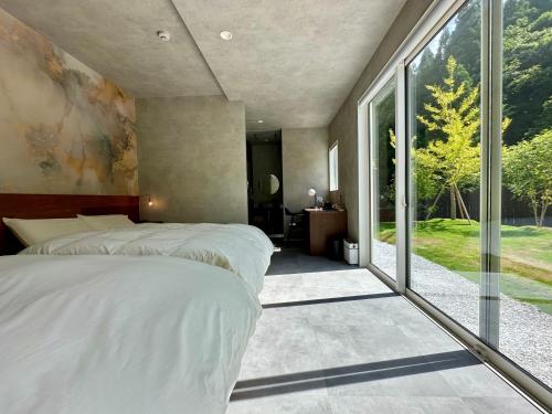 a bedroom with a bed and a large window at LOCA THE JUNPU Moroyose in Moroyose