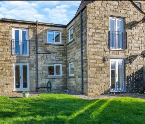 a brick house with a green lawn in front of it at Ingledale Apartment, Ingleton, Yorkshire Dales National Park, Famous Three Peaks, Near The Lake District, Pets Are Welcome in Ingleton 