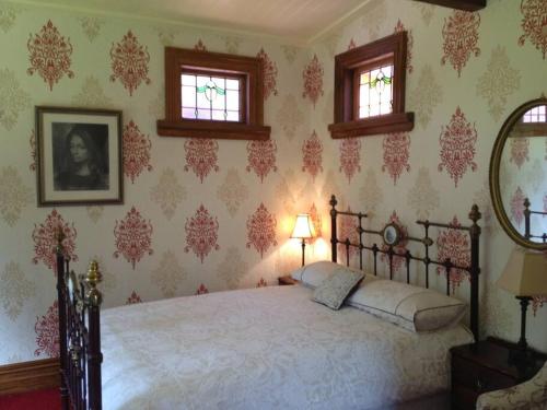 ein Schlafzimmer mit einem Bett und zwei Fenstern in der Unterkunft Oakura Pond Cottage - A unique kiwi holiday Bach in Oakura