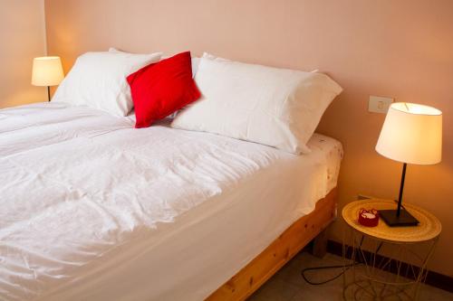 a white bed with two red pillows and two lamps at Poppy B&B vicino alla Fiera di Bologna in Bologna