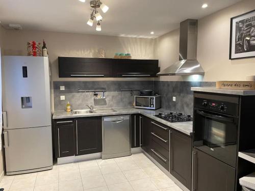 une cuisine avec un réfrigérateur blanc et un évier dans l'établissement Maison familiale, emplacement idéal, à Aigneville
