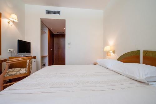 a bedroom with a white bed and a television at Fthia Hotel in Lamía