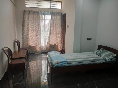 a bedroom with a bed and a table and a window at Mansons Homestay in Siliguri
