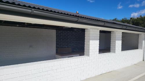 a brick building with two windows and a roof at Husky 19 Beautifully Appointed Apartments - GREAT LOCATION - in the heart of Husky in Huskisson