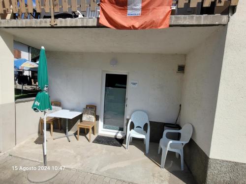 a balcony with chairs and a table and an umbrella at casa Battilana Li Curt - Poschiavo in Prada