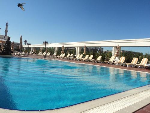 a large swimming pool with chairs and a building at Buyukhanli Park Hotel in Ankara