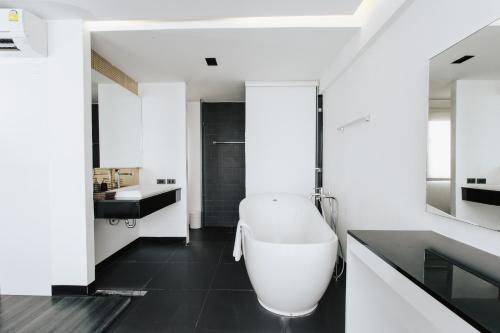 a bathroom with a white tub and a sink at NANEE Phra Singh in Chiang Mai