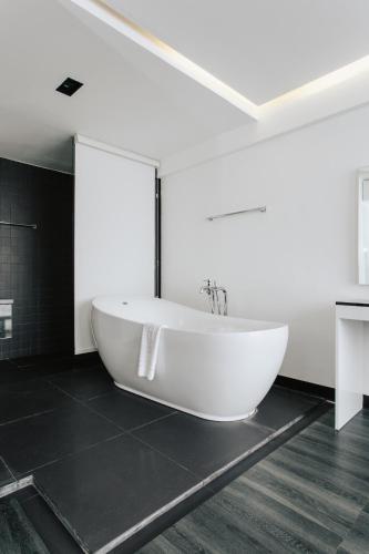 a white bath tub in a bathroom with black tiles at NANEE Phra Singh in Chiang Mai